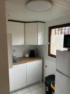 a kitchen with white cabinets and a sink and a window at Appartement meublé indépendant Parking privé Proche gare & Paris in Mériel