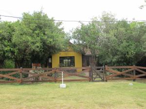 a wooden fence in front of a yellow house at Cabaña Los Pololos in Villa Serrana