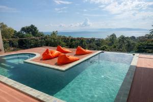une piscine avec des coussins orange installés sur une terrasse dans l'établissement NAHA Villa Sea View Koh Phangan, à Baan Tai