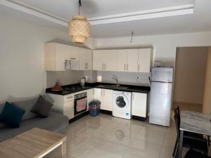 a kitchen with white cabinets and a washer and dryer at Cozy apartment adana in Aourir