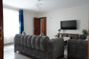 een woonkamer met een bank en een televisie bij Modern Kisumu Apartment Near Airport, Malls & Lake Victoria in Kisumu