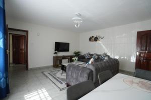 een woonkamer met een bank en een tafel bij Modern Kisumu Apartment Near Airport, Malls & Lake Victoria in Kisumu +38 foto's