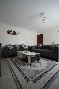 een woonkamer met twee banken en een salontafel bij Modern Kisumu Apartment Near Airport, Malls & Lake Victoria in Kisumu