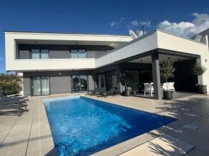 une maison avec une piscine devant dans l'établissement Villa TEREZA Luxury Sea View Villa for Families & Romantic Getaways, à Sveti Vid-Miholjice