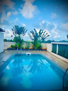 einen Pool mit blauem Wasser und Palmen in der Unterkunft Riviera Retreat villa in Mahabalipuram