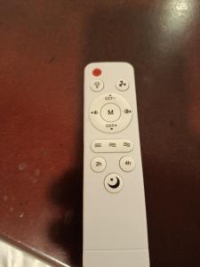 a white remote control sitting on top of a table at Quarto 11 casa in Campina Grande