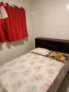 a small bedroom with a bed with a floral blanket at Quarto 11 casa in Campina Grande