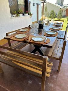un tavolo di legno con sopra piatti e bicchieri da vino di Las Cortaderas House a Trancas Altre 3 foto