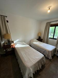 una camera con due letti, due lampade e una finestra di Las Cortaderas House a Trancas