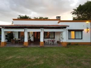 a white house with a table and chairs in a yard at Las Cortaderas House in Trancas