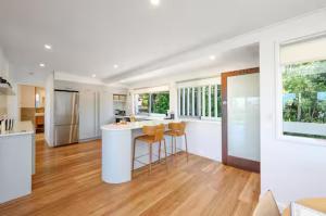 a kitchen with white walls and wooden floors at Noosa Escape 2BR Ocean Views, Walk to Beach in Noosa Heads