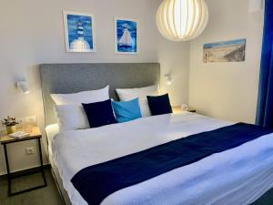 a bedroom with a large bed with blue and white pillows at Am Horizont No 3 für 2-4 Pers, 2 Schlafz, Garten, Strandkorb, Grill, Parkplatz, am Haus in Zingst