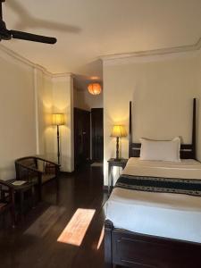 ein Schlafzimmer mit einem Bett, einem Schreibtisch und zwei Lampen in der Unterkunft Hotel Khamvongsa in Vientiane