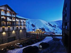 eine Gruppe von Autos, die auf einem Parkplatz vor einem Gebäude geparkt sind in der Unterkunft Apartment Spartak in Gudauri