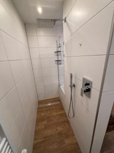 a bathroom with white tile walls and a shower stall at Schildetal Apartment 1 in Camin +17 photos
