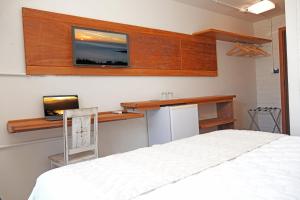 una camera da letto con un letto e una TV a parete di Pousada da Encosta a Garopaba