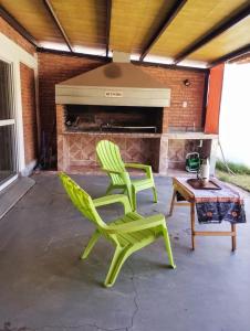 twee groene stoelen en een tafel voor een open haard bij Casa quincho don Octavio in La Carrera