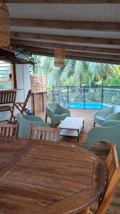 een terras met een tafel en stoelen en een zwembad bij Le Havre du Voyageur - Colibri in Le Moule