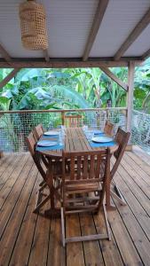 een houten tafel en stoelen op een houten terras bij Le Havre du Voyageur - Colibri in Le Moule