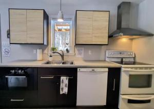 a kitchen with black and white appliances and a sink at Chalet de la Roche Plate in Saint-Raymond +37 photos