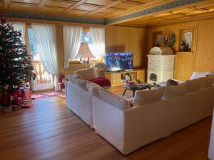 a living room with white couches and a christmas tree at Chalet Luxury Pelmo in San Vito di Cadore
