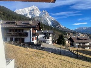 a house in a field with mountains in the background at Chalet Luxury Pelmo in San Vito di Cadore
