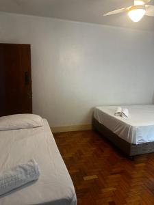 a room with two beds and a ceiling fan at Oxx in Congonhas