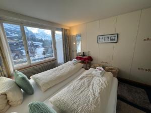 two beds in a room with a large window at Guest Rooms with a great view at Residence Brunner in Wengen +60 photos