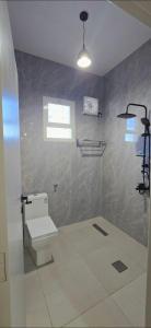 a bathroom with a toilet and a shower with a window at شقق النزهة الفندقيه in Riyadh Al Khabra
