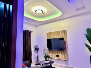 een woonkamer met een televisie en een tafel met bloemen bij De Generals Hotel in Ibadan +25 foto's