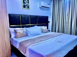 een slaapkamer met een groot bed met een zwart hoofdeinde bij De Generals Hotel in Ibadan