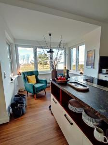 a kitchen with a counter with a blue chair and windows at Ferienhaus Zur Oie in Bresewitz