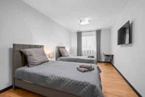 a bedroom with two beds and a flat screen tv at Centrum Prestige Apartments in Rybnik