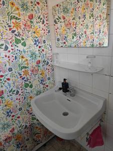 - un lavabo blanc dans la salle de bains avec papier peint floral dans l'établissement Cricri, à Lelystad 11 autres photos