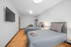 a bedroom with two beds and a flat screen tv at Centrum Prestige Apartments in Rybnik +24 photos