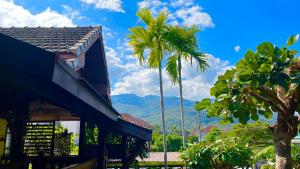 ein Haus mit Palmen und Bergen im Hintergrund in der Unterkunft SJ house Unique wood Thai style in Chiang Mai + 17 Fotos