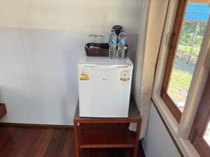 einen kleinen weißen Kühlschrank in einem Zimmer mit einem Tisch in der Unterkunft Mook Happy Bungalow in Ko Mook