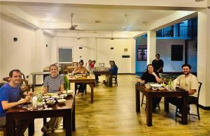 a group of people sitting at tables in a restaurant at Man Guest Polonnaruwa in Polonnaruwa