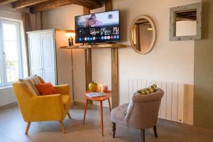 een woonkamer met 2 stoelen en een flatscreen-tv bij Studio Pop-25m2-Neuf et coloré - WiFi-Netflix in Bellême