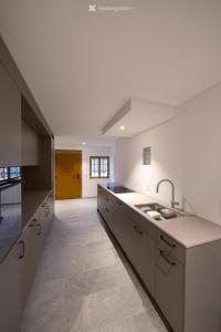 une grande cuisine blanche avec un évier et un comptoir dans l'établissement Historisches Bijou in Beromünster, Golf & Luzern, à Beromünster