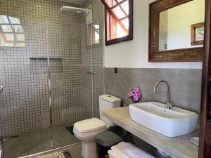 ein Badezimmer mit Waschbecken, Toilette und Spiegel in der Unterkunft Pousada Sete Quedas in Carrancas
