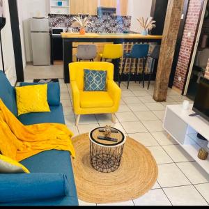 een woonkamer met een blauwe bank en gele stoelen bij Cosy atelier in Vierzon