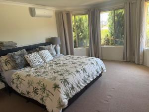 a bedroom with a bed with a blanket and windows at Bertram Family Retreat in Wellard