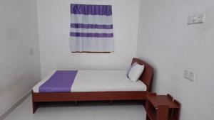 a small bed in a white room with at Priya Villa Homestay in Jaffna