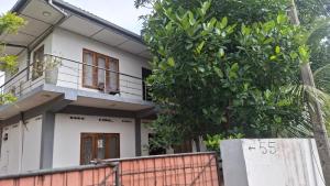 a white house with a tree in front of it at Priya Villa Homestay in Jaffna