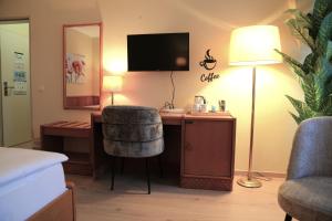 a room with a desk with a chair and a lamp at Hotel Bentheimer Eck in Bad Bentheim