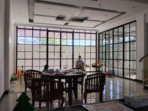 a dining room with a table and chairs and windows at RADJIMIN Guesthouse in Adi Sutjipto