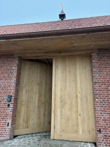 a pair of wooden garage doors on a brick building at Tjusteplekske in Heuvelland