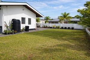 a backyard of a white house with a lawn at Maison Meredith in Paramaribo