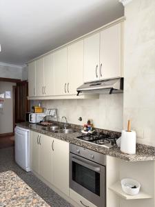 a kitchen with white cabinets and a stove top oven at BARRAMARES 3 in Furadouro